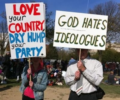 God hates this guy's hypocrisy and false sign. Oh and the self-righteousness too. That other sign is so... what's the word... classy! Only a classy person would hold that sign. But in all seriousness this guy wouldn't know God if He was right in front of him in the flesh. It's funny how leftists use the rhetoric of religion for their hatred toward others but really don't believe in God.